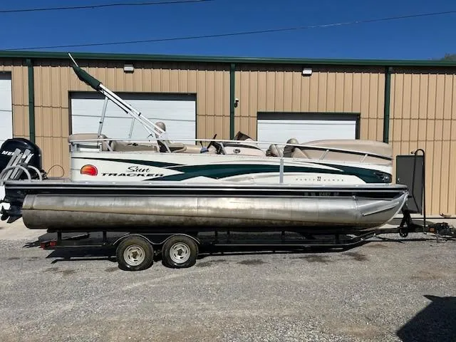 Slide: The Image of 2010 Sun Tracker PARTY BARGE 22 Regency Edition pontoon boat on trailer, parked outdoors. - 23