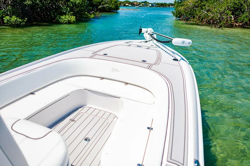 Slide: The Image of 2023 Contender 25 Bay boat on clear turquoise water, surrounded by lush greenery. - 10