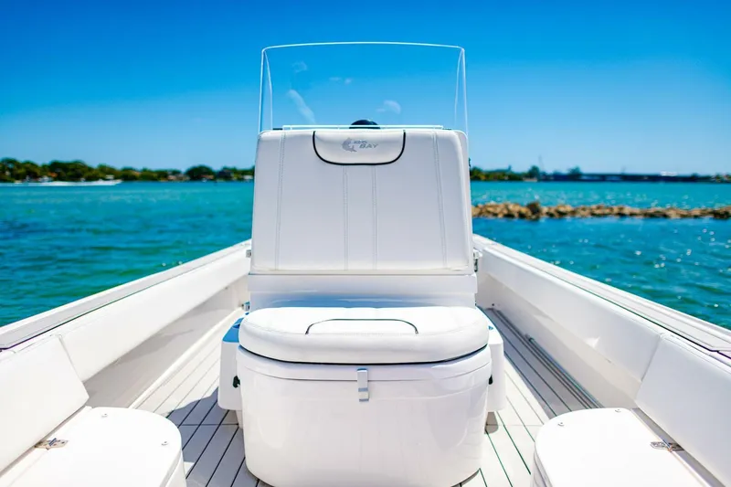 Slide: The Image of 2023 Contender 25 Bay boat on clear blue water, featuring sleek white seating. - 14