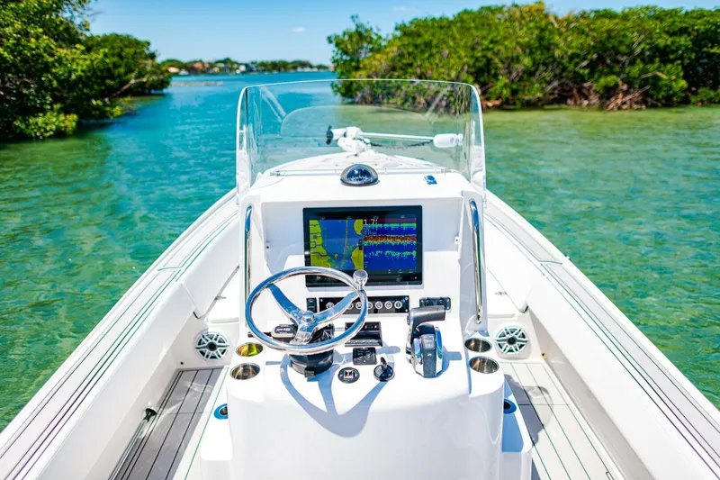 Slide: The Image of 2023 Contender 25 Bay boat navigating clear waters with advanced dashboard. - 20