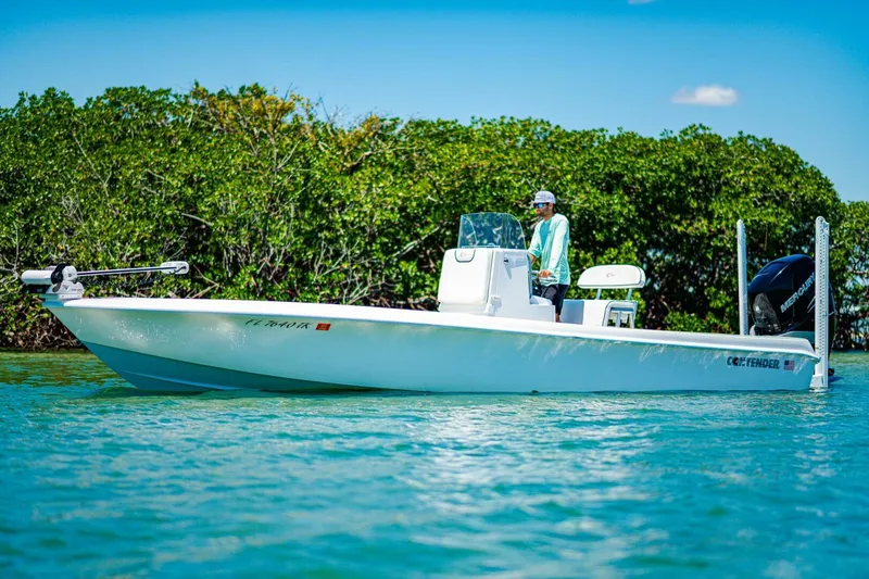 Slide: The Image of 2023 Contender 25 Bay boat on water, surrounded by lush greenery. - 35