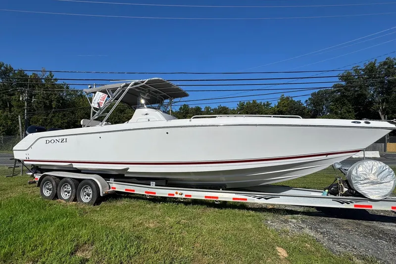 The Image of 2008 Donzi 35ZX boat on trailer, white with red accents, parked on grass. - 0