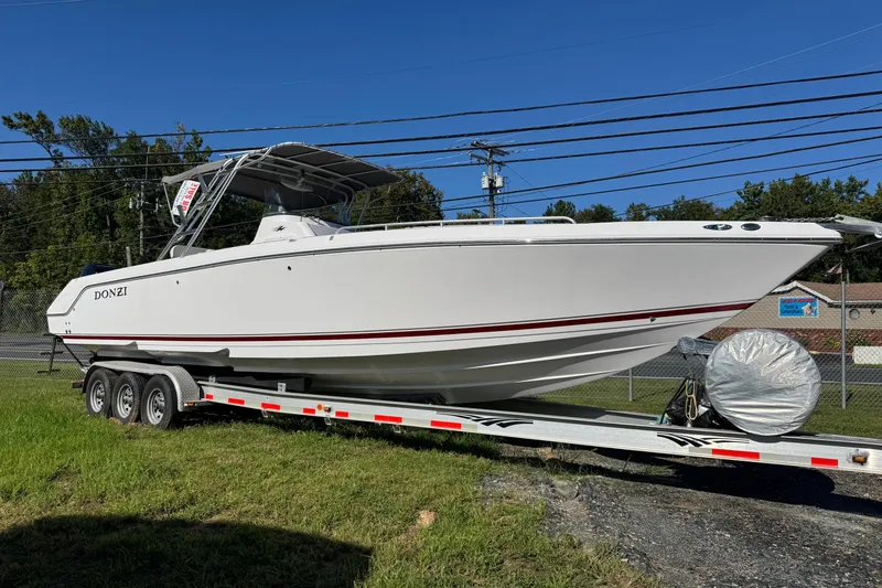 Slide: The Image of 2008 Donzi 35ZX boat on trailer, white with red stripe, parked outdoors. - 2