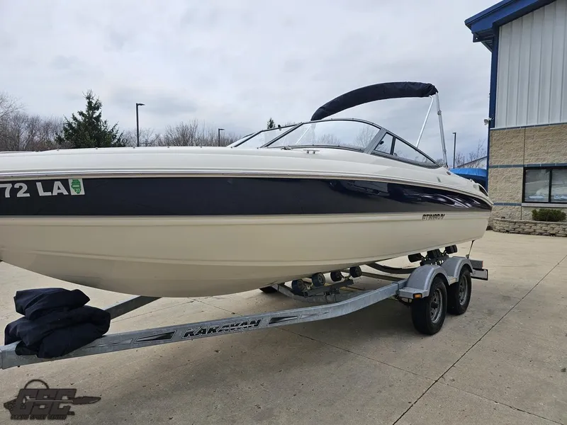 Slide: The Image of 2013 Stingray 225 LR boat on trailer, parked outdoors near a building. - 20