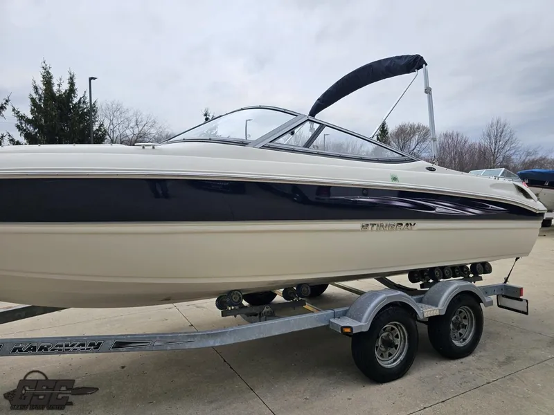 Slide: The Image of 2013 Stingray 225 LR boat on trailer, featuring sleek design and bimini top. - 22