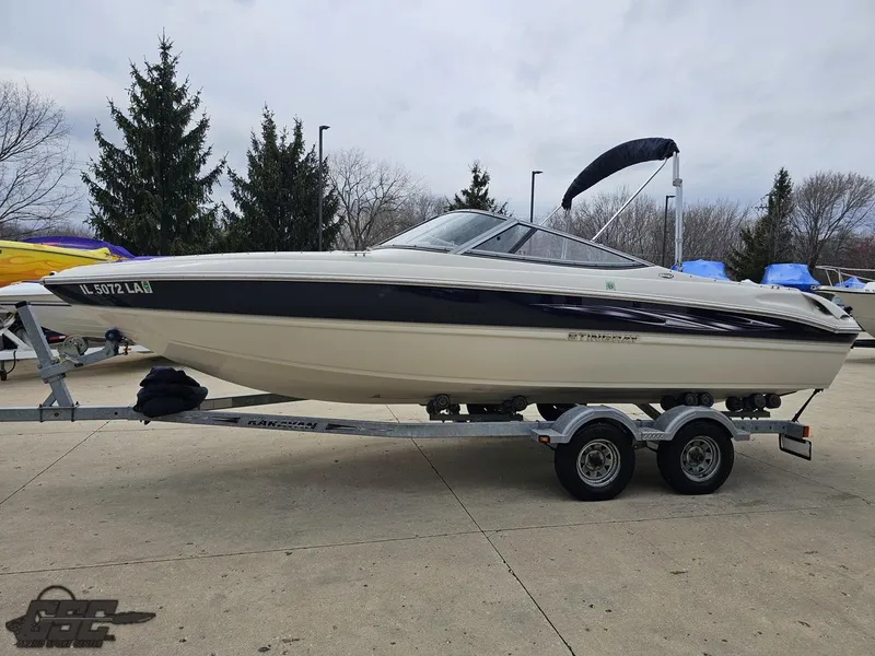 Slide: The Image of 2013 Stingray 225 LR boat on trailer, parked outdoors. - 24