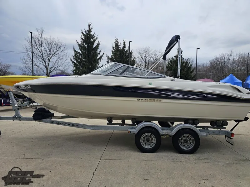 Slide: The Image of 2013 Stingray 225 LR boat on trailer, parked outdoors. - 25
