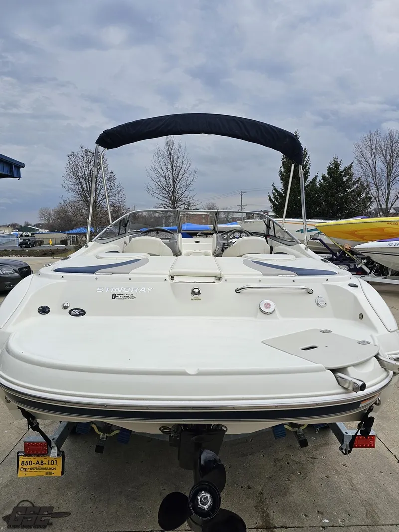 Slide: The Image of 2013 Stingray 225 LR boat with bimini top, docked outdoors. - 30