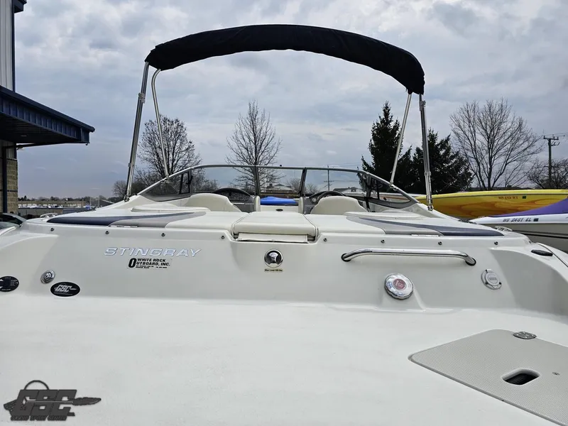 Slide: The Image of 2013 Stingray 225 LR boat with canopy, docked under cloudy skies. - 33