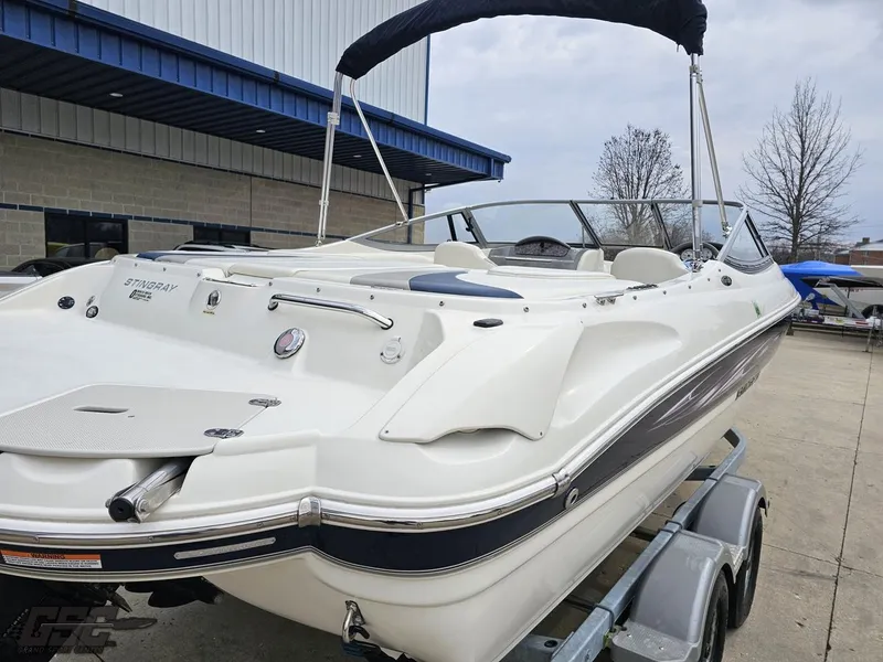 Slide: The Image of 2013 Stingray 225 LR boat on trailer, white exterior, parked outdoors. - 34