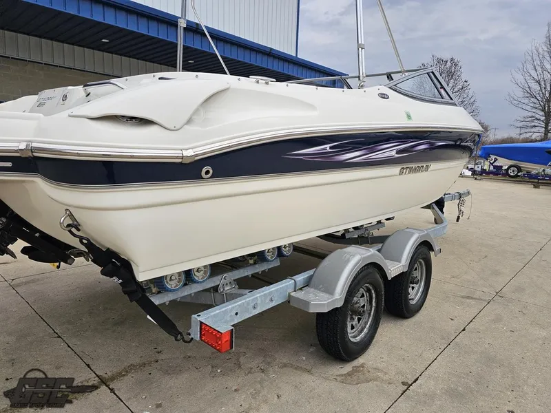 Slide: The Image of 2013 Stingray 225 LR boat on trailer, parked outdoors near a building. - 35