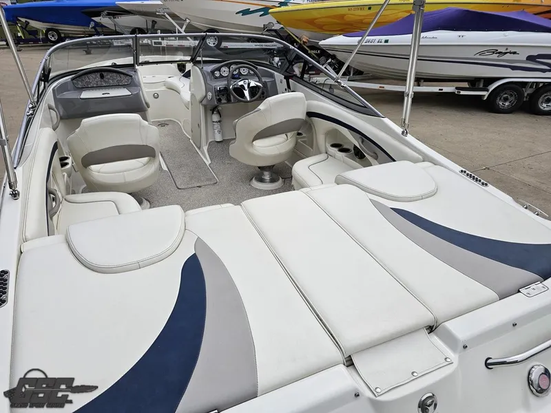 Slide: The Image of 2013 Stingray 225 LR boat interior with white seating and dashboard, docked alongside other boats. - 37