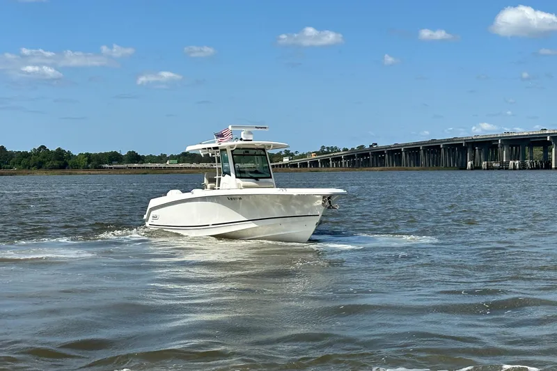 Slide: The Image of 2021 Boston Whaler 330 Outrage cruising on a river near a bridge under a clear sky. - 11