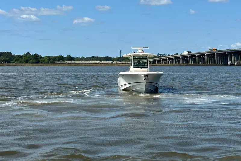 Slide: The Image of 2021 Boston Whaler 330 Outrage boat cruising on a river near a bridge under a clear sky. - 12