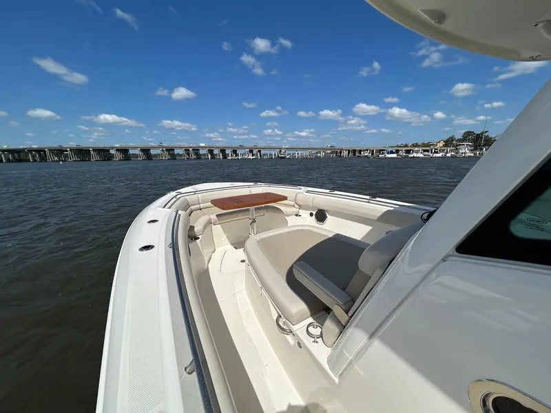 Slide: The Image of 2021 Boston Whaler 330 Outrage boat on water, featuring spacious seating and clear skies. - 16