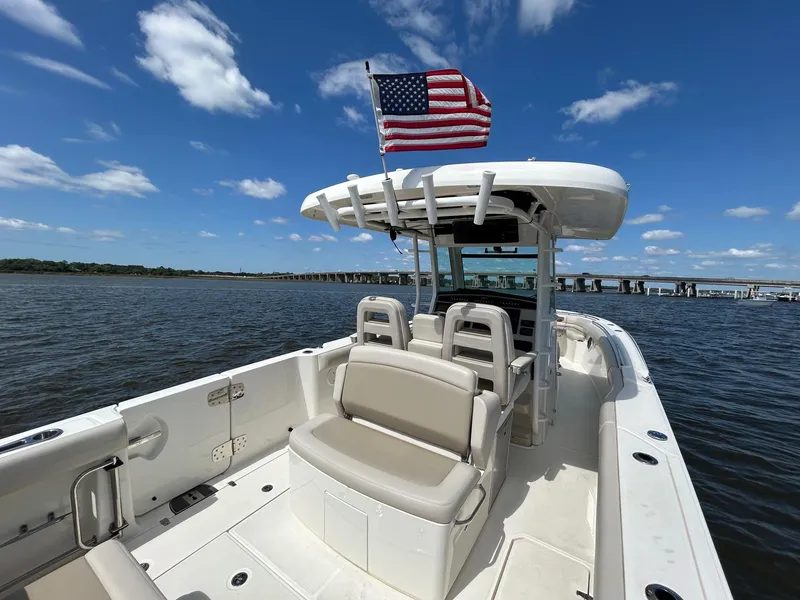 Slide: The Image of 2021 Boston Whaler 330 Outrage boat with American flag on open water under blue sky. - 20