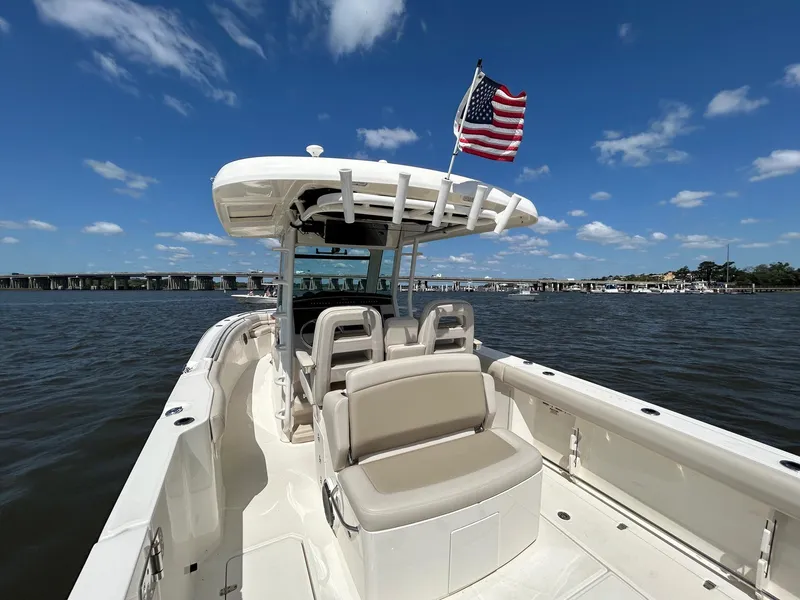 Slide: The Image of 2021 Boston Whaler 330 Outrage boat on water, American flag, clear sky. - 25