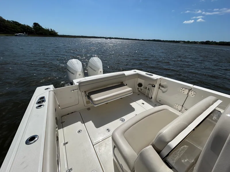 Slide: The Image of 2021 Boston Whaler 330 Outrage boat on calm water, featuring spacious deck and twin engines. - 26