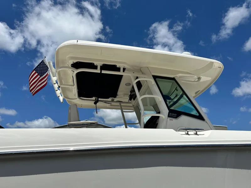 Slide: The Image of 2021 Boston Whaler 330 Outrage boat with American flag against blue sky. - 28