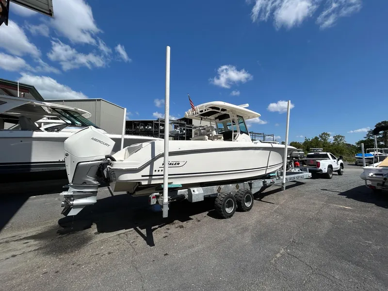 Slide: The Image of 2021 Boston Whaler 330 Outrage boat on trailer, parked outdoors under a clear blue sky. - 29