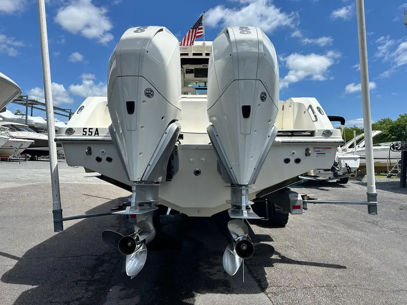 Slide: The Image of 2021 Boston Whaler 330 Outrage with dual outboard engines, docked under a clear blue sky. - 30
