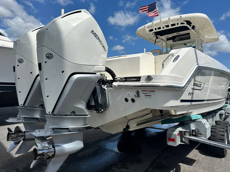Slide: The Image of 2021 Boston Whaler 330 Outrage boat with dual Mercury engines, docked under a clear sky. - 31