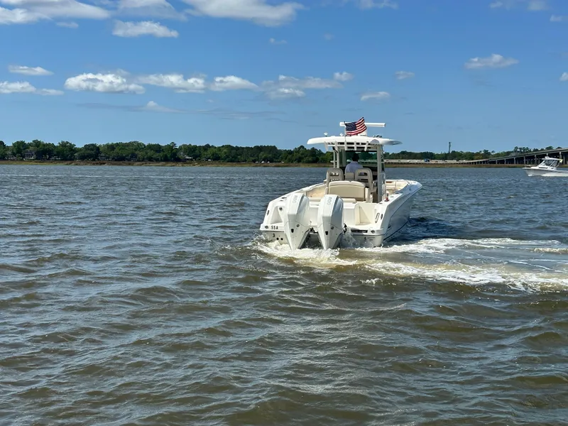 Slide: The Image of 2021 Boston Whaler 330 Outrage cruising on a sunny day with American flag. - 4