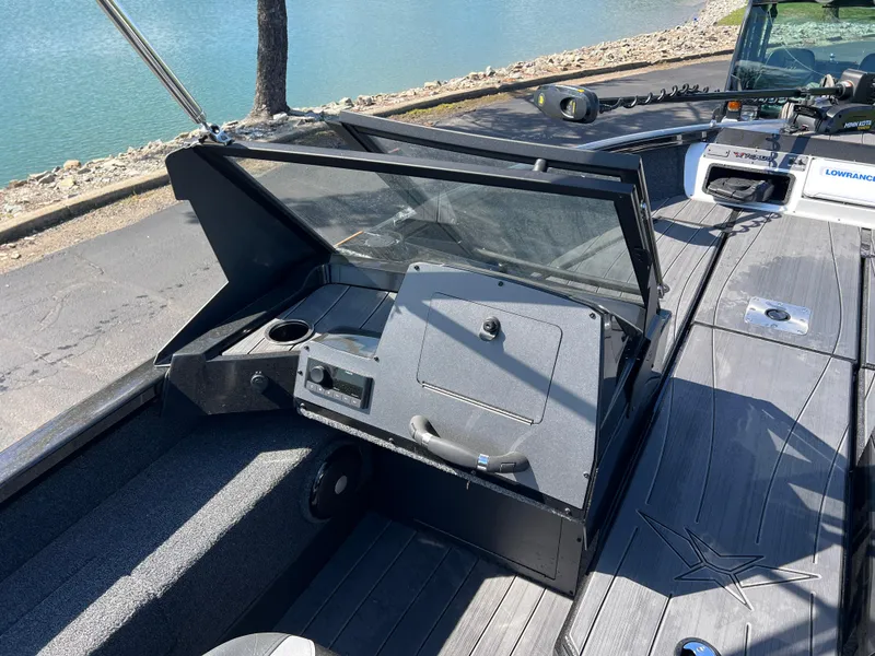 Slide: The Image of 2025 Vexus ADX190 boat interior with open storage compartment and cup holder by the water. - 16