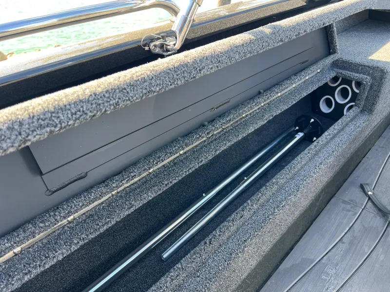 Slide: The Image of 2025 Vexus ADX190 boat storage compartment with rod holders and carpeted interior. - 28