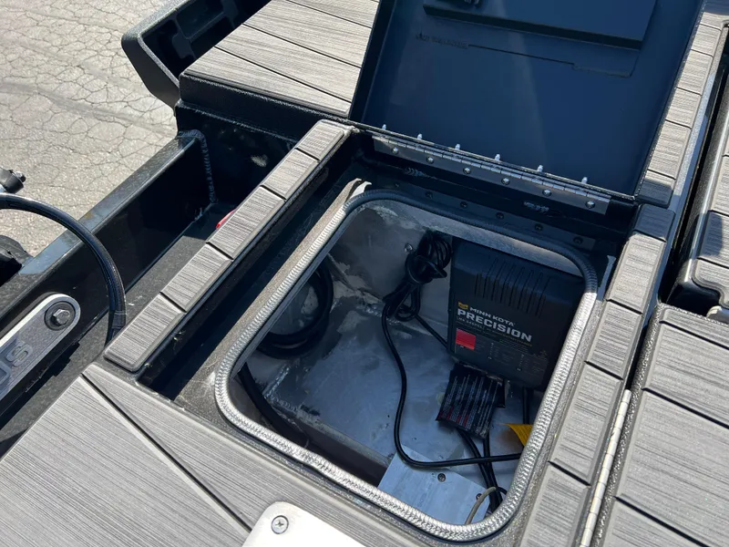Slide: The Image of Open storage compartment in 2025 Vexus ADX190 boat, showing battery charger and cables. - 33