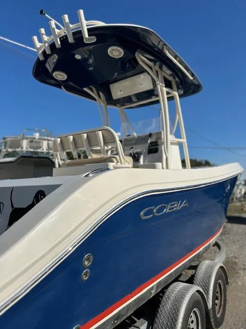Slide: The Image of 2015 Cobia 237 Center Console boat with blue hull and T-top on a trailer. - 5