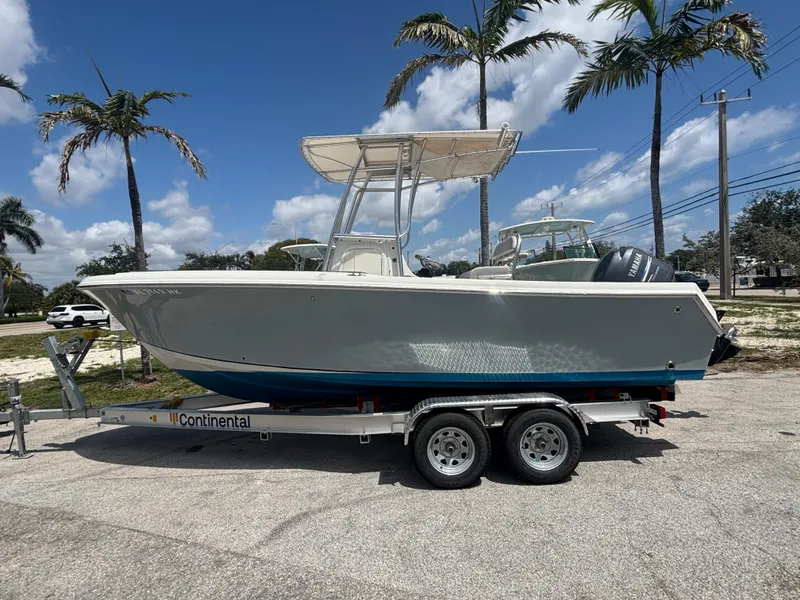Slide: The Image of 2007 Sailfish 218 CC boat on trailer, parked under palm trees, clear sky background. - 4