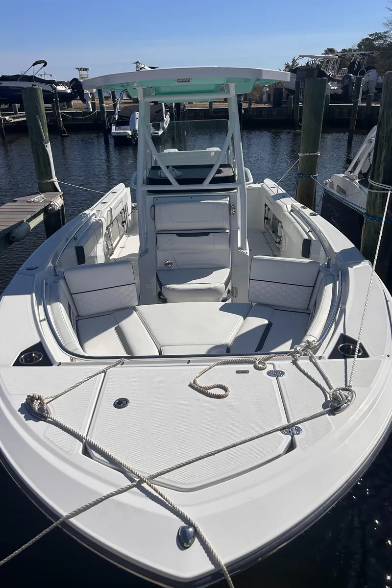 Slide: The Image of 2021 Blackfin 252 CC boat docked at marina, showcasing sleek design and spacious seating. - 2