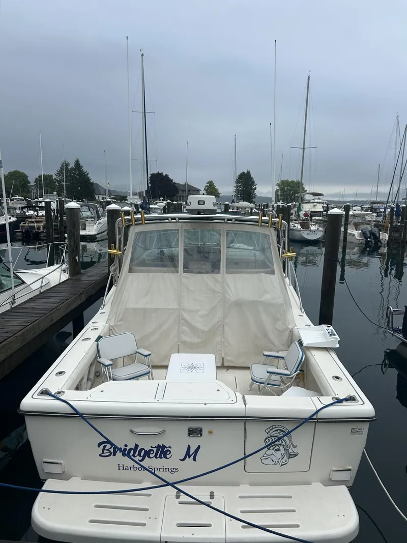 The Image of 1998 Pursuit 3400 Express boat docked at marina, overcast sky, named "Bridgette M". - 0