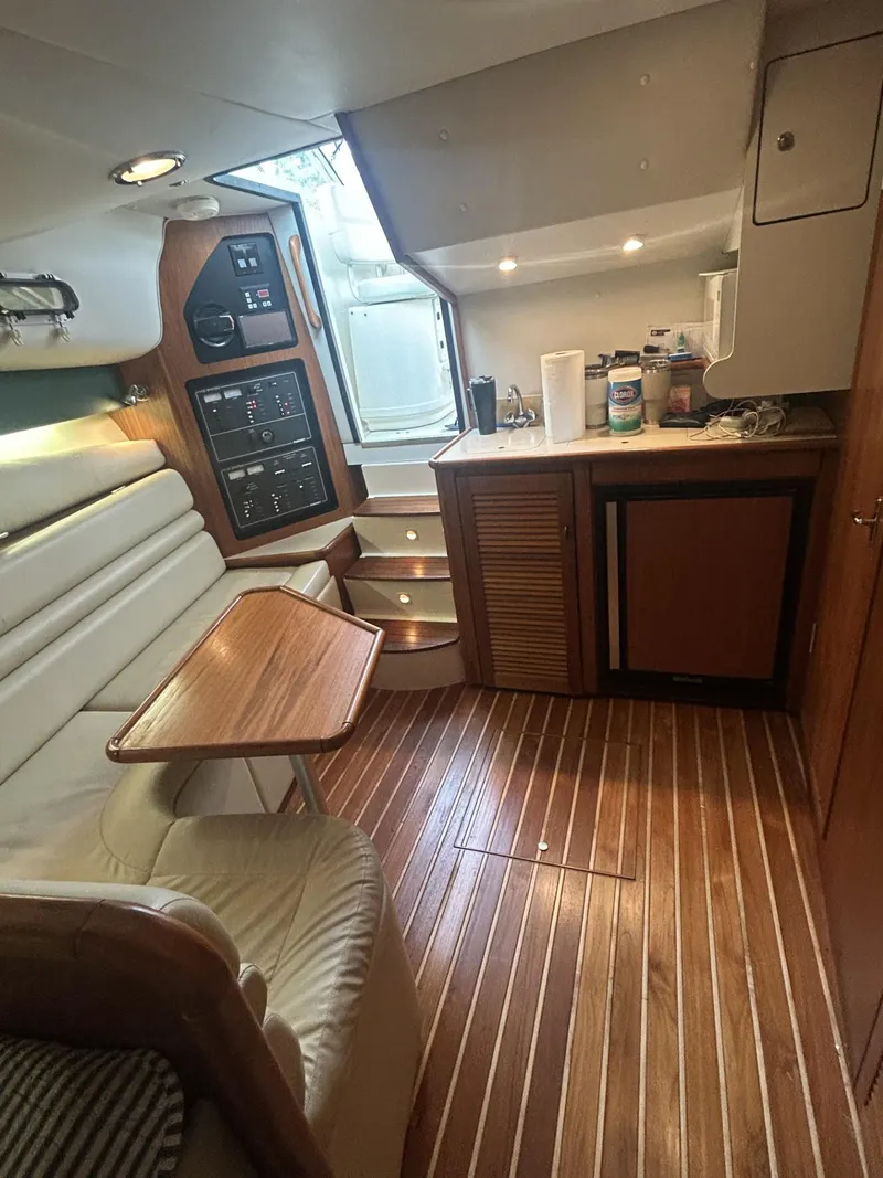 Slide: The Image of 1998 Pursuit 3400 Express cabin interior with wood flooring, seating, and kitchenette. - 10
