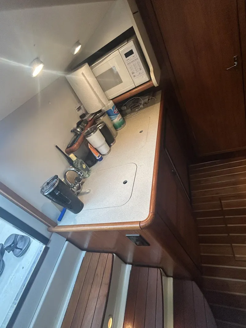Slide: The Image of 1998 Pursuit 3400 Express boat interior kitchen with microwave and wooden cabinetry. - 11