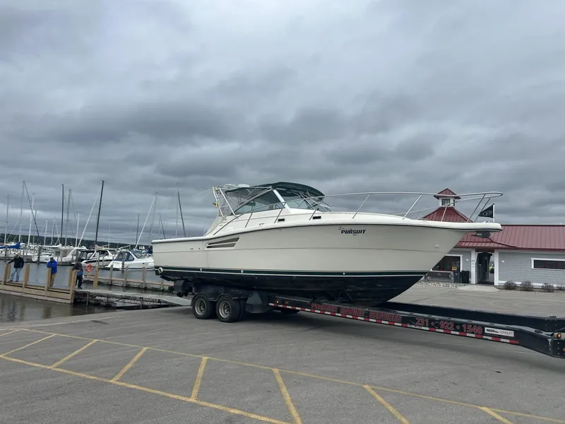 Slide: The Image of 1998 Pursuit 3400 Express boat on trailer at marina under cloudy sky. - 2