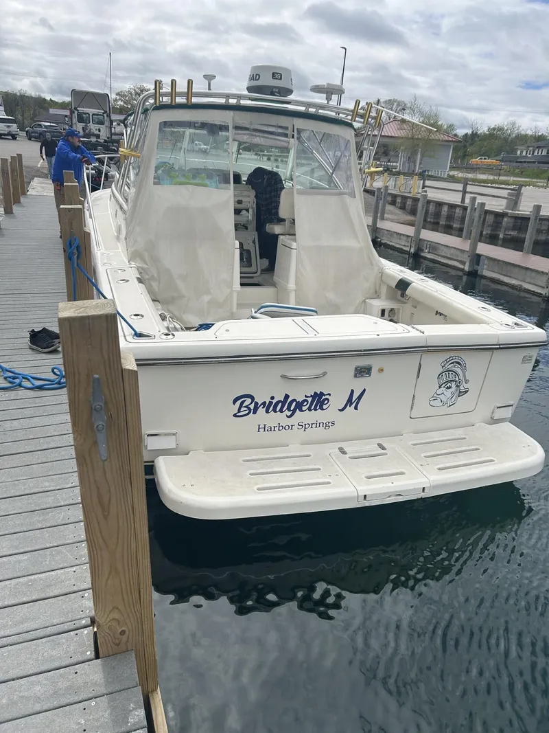 Slide: The Image of 1998 Pursuit 3400 Express boat docked, featuring open deck and cabin, named "Bridgette M". - 3