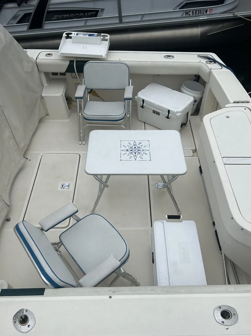 Slide: The Image of 1998 Pursuit 3400 Express boat deck with chairs, table, and cooler. - 5