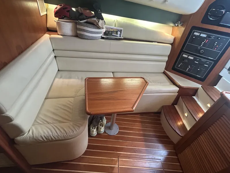 Slide: The Image of 1998 Pursuit 3400 Express cabin with wooden table, cushioned seating, and control panel. - 9