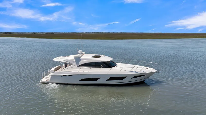 Slide: The Image of 2020 Riviera 4800 Sport Yacht cruising on calm waters under a clear blue sky. - 0