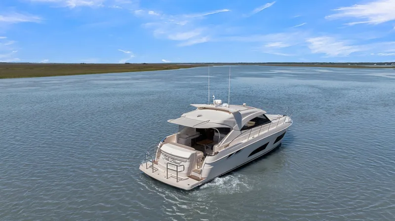 Slide: The Image of 2020 Riviera 4800 Sport Yacht cruising on a calm, scenic waterway under a clear blue sky. - 12