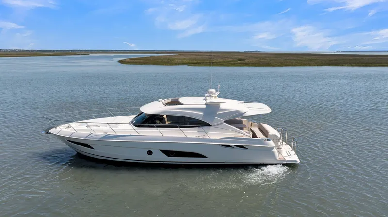 Slide: The Image of 2020 Riviera 4800 Sport Yacht cruising on calm waters under a clear blue sky. - 4