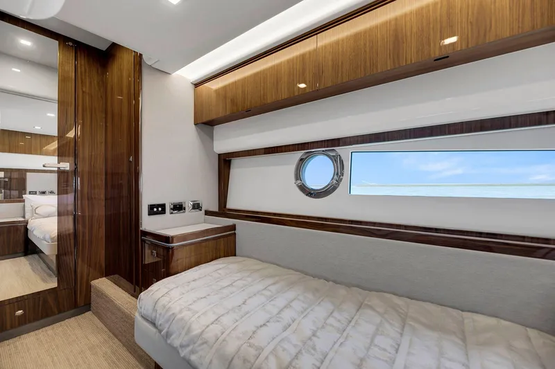 Slide: The Image of 2020 Riviera 4800 Sport Yacht cabin with wood accents and porthole window. - 44