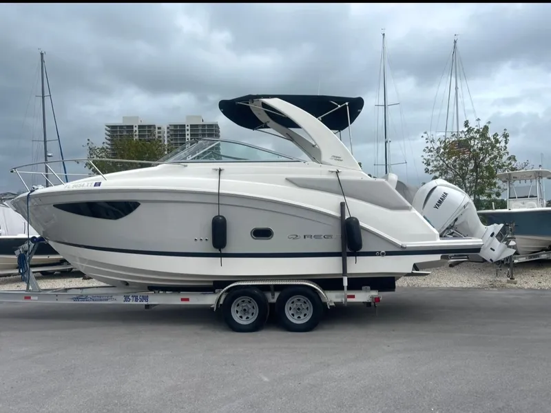 Slide: The Image of 2024 Regal 26 XO boat on trailer, parked outdoors under cloudy sky. - 0