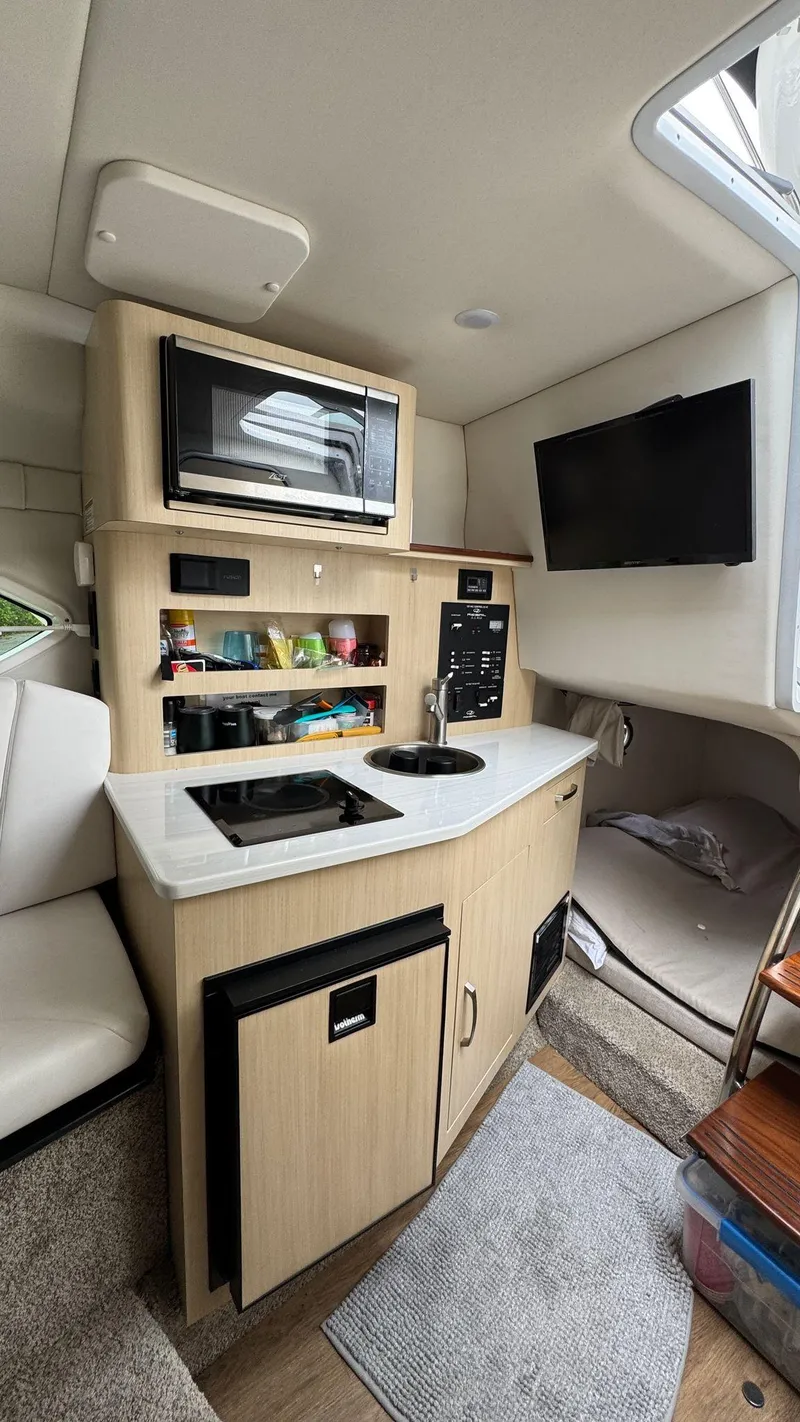 Slide: The Image of 2024 Regal 26 XO boat interior with kitchenette, microwave, TV, and storage. - 17