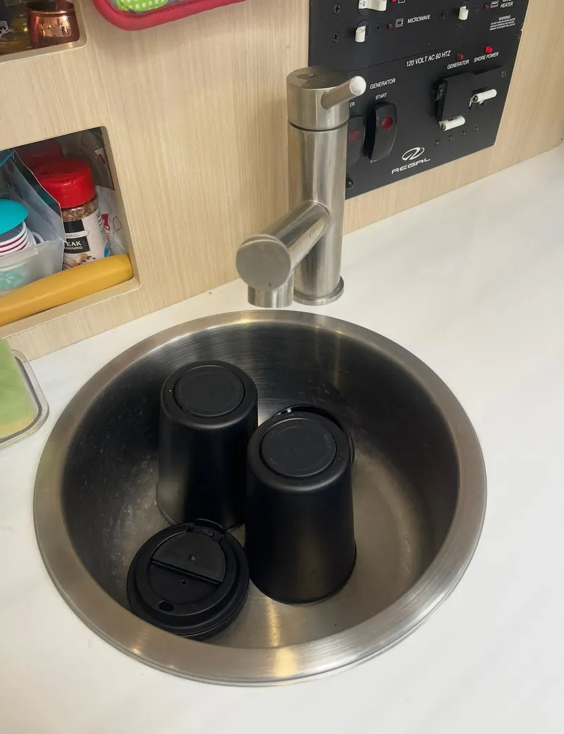 Slide: The Image of Stainless steel sink with black cups in a 2024 Regal 26 XO boat interior. - 21