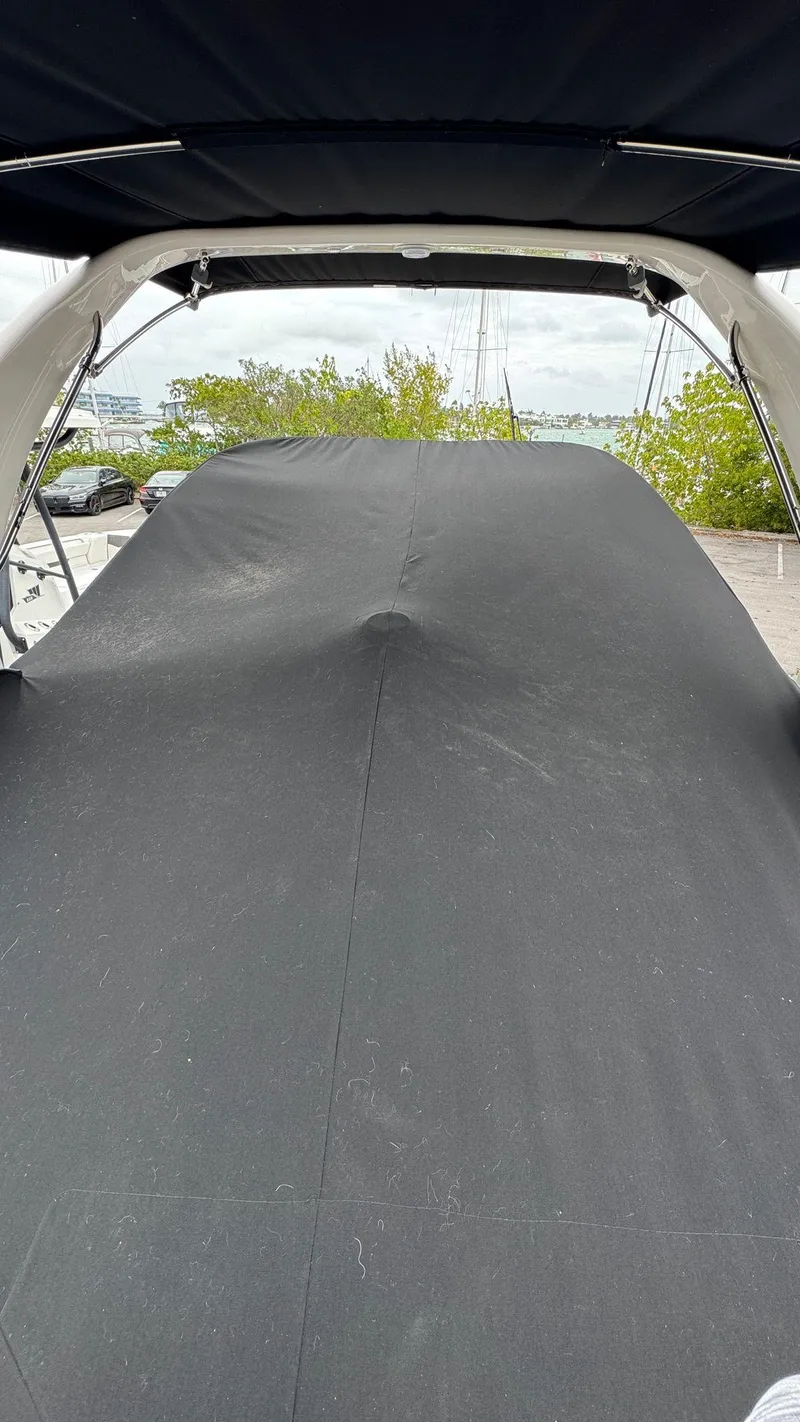 Slide: The Image of 2024 Regal 26 XO boat with black cover, docked near greenery. - 5