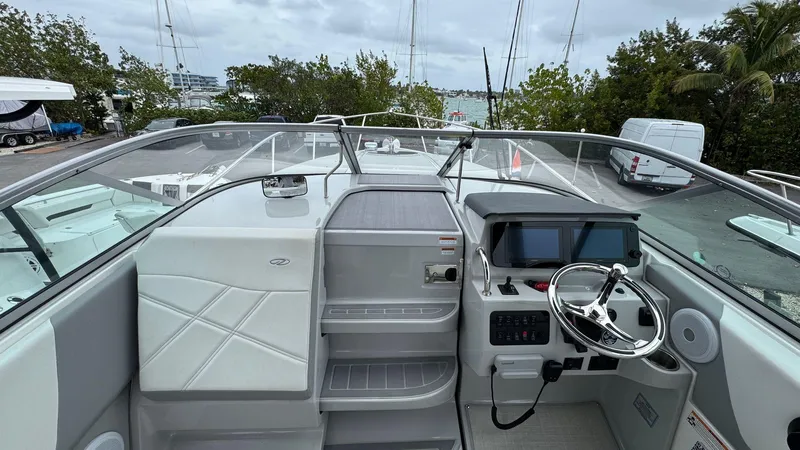 Slide: The Image of 2024 Regal 26 XO boat cockpit with modern controls and seating, docked near trees and water. - 9