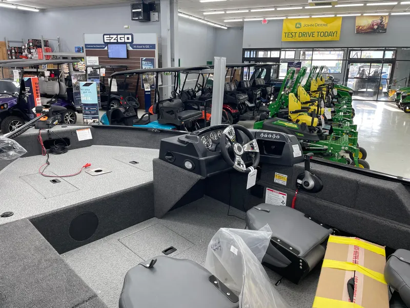 Slide: The Image of 2025 Lowe FM1675S boat interior in showroom with various vehicles in background. - 10